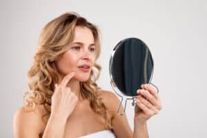 A woman looking at acne in the mirror